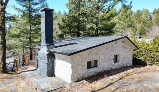 Place pour feu extérieur à gauche du chalet et grand balcon en hauteur face au lac