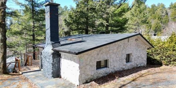 Place pour feu extérieur à gauche du chalet et grand balcon en hauteur face au lac